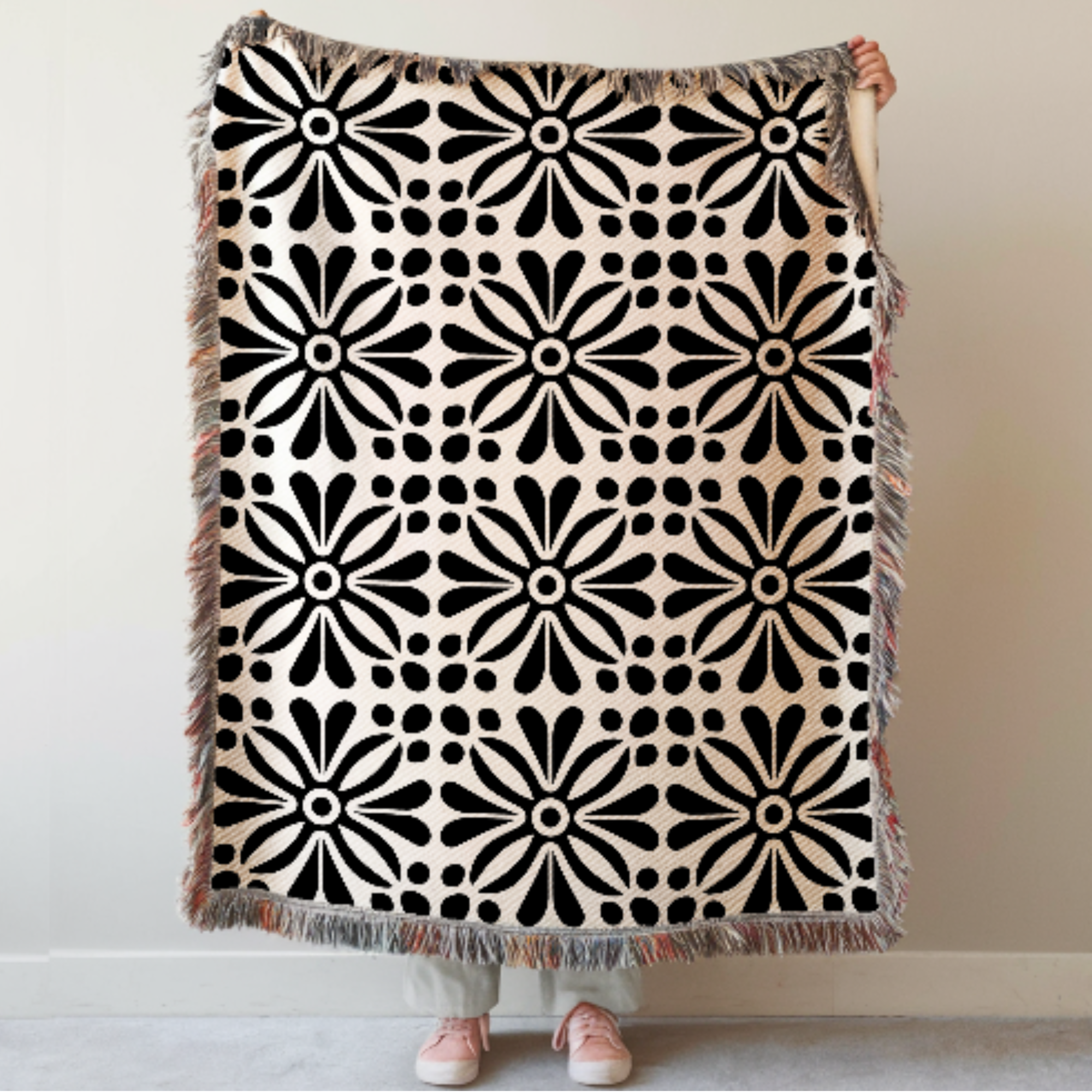 Black Abstract Floral Woven Blanket held by a person against a plain background