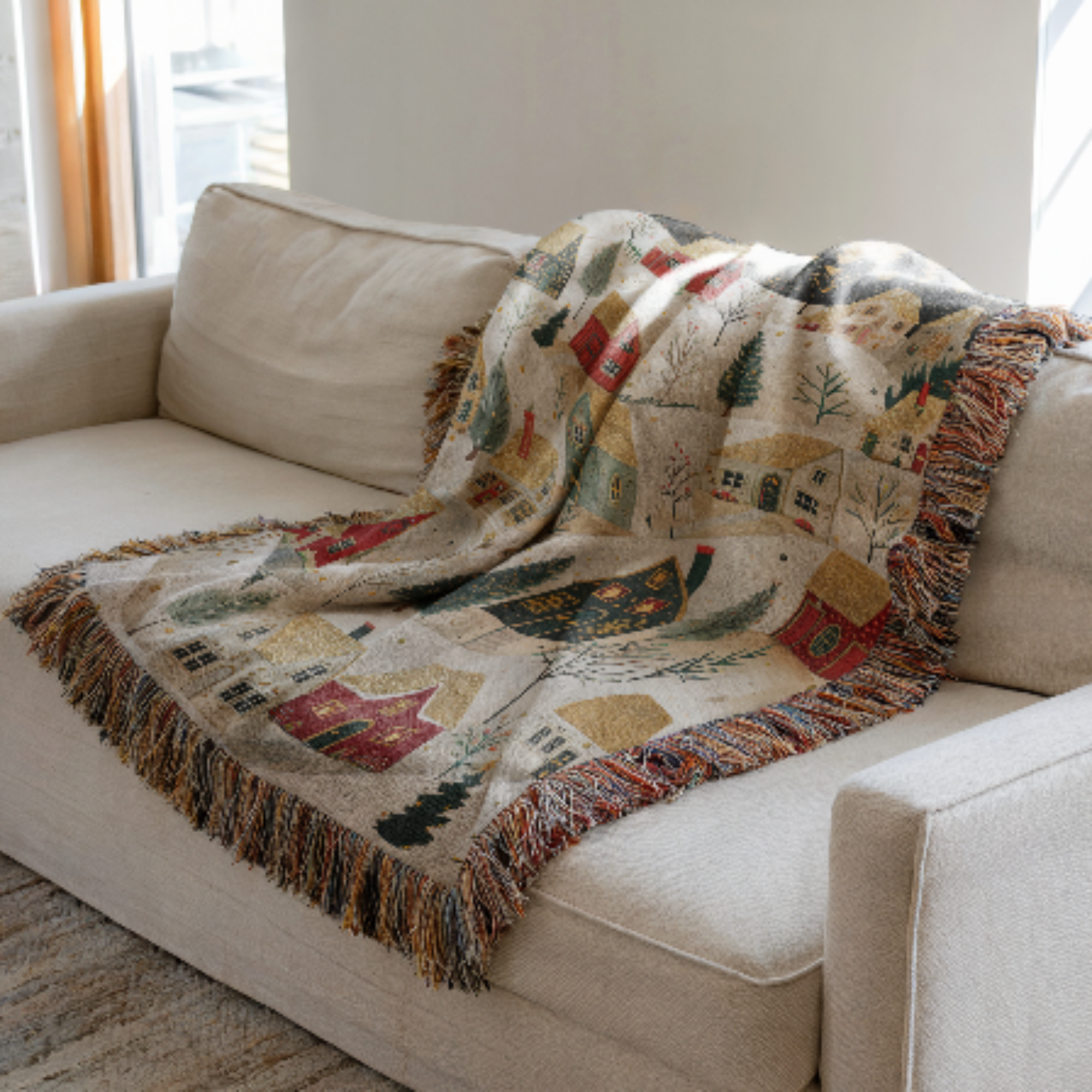 Christmas Woven Blanket with a winter scene on a beige sofa.