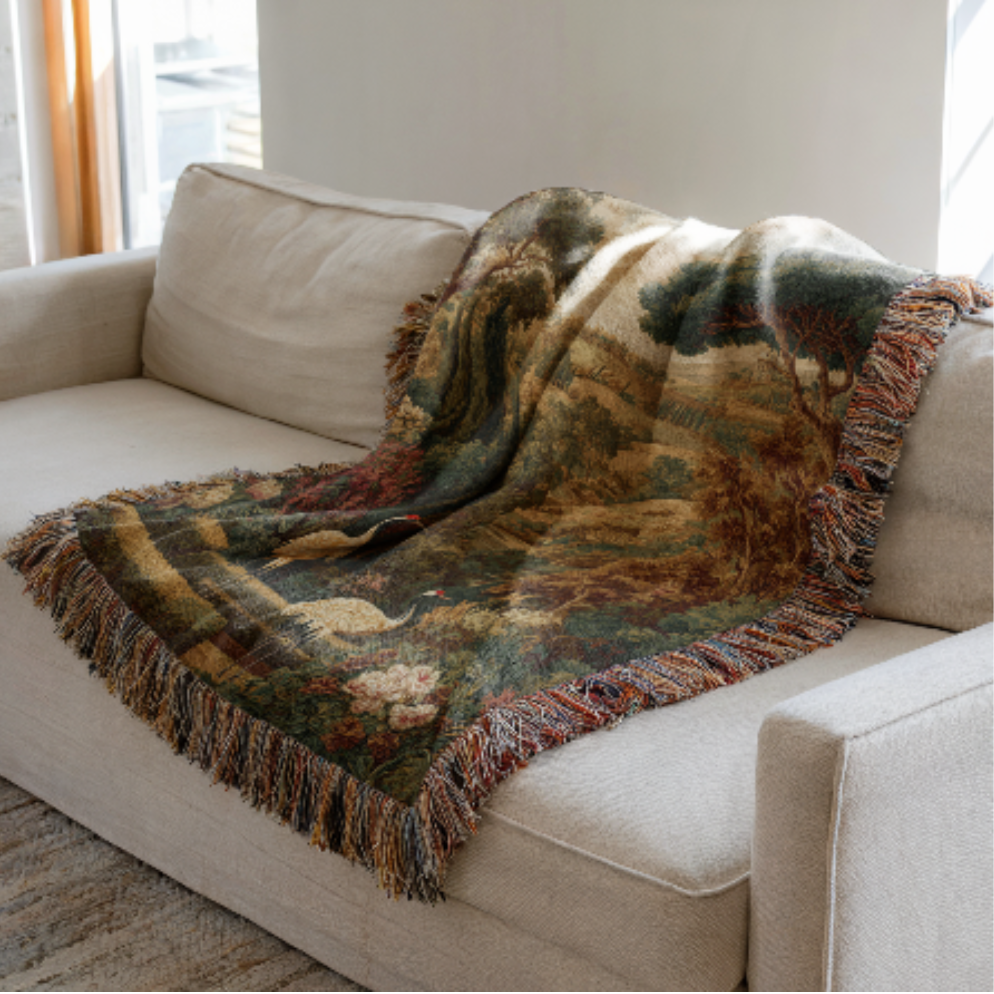 Decorative blanket with a french landscape nature-themed pattern draped over a beige sofa.