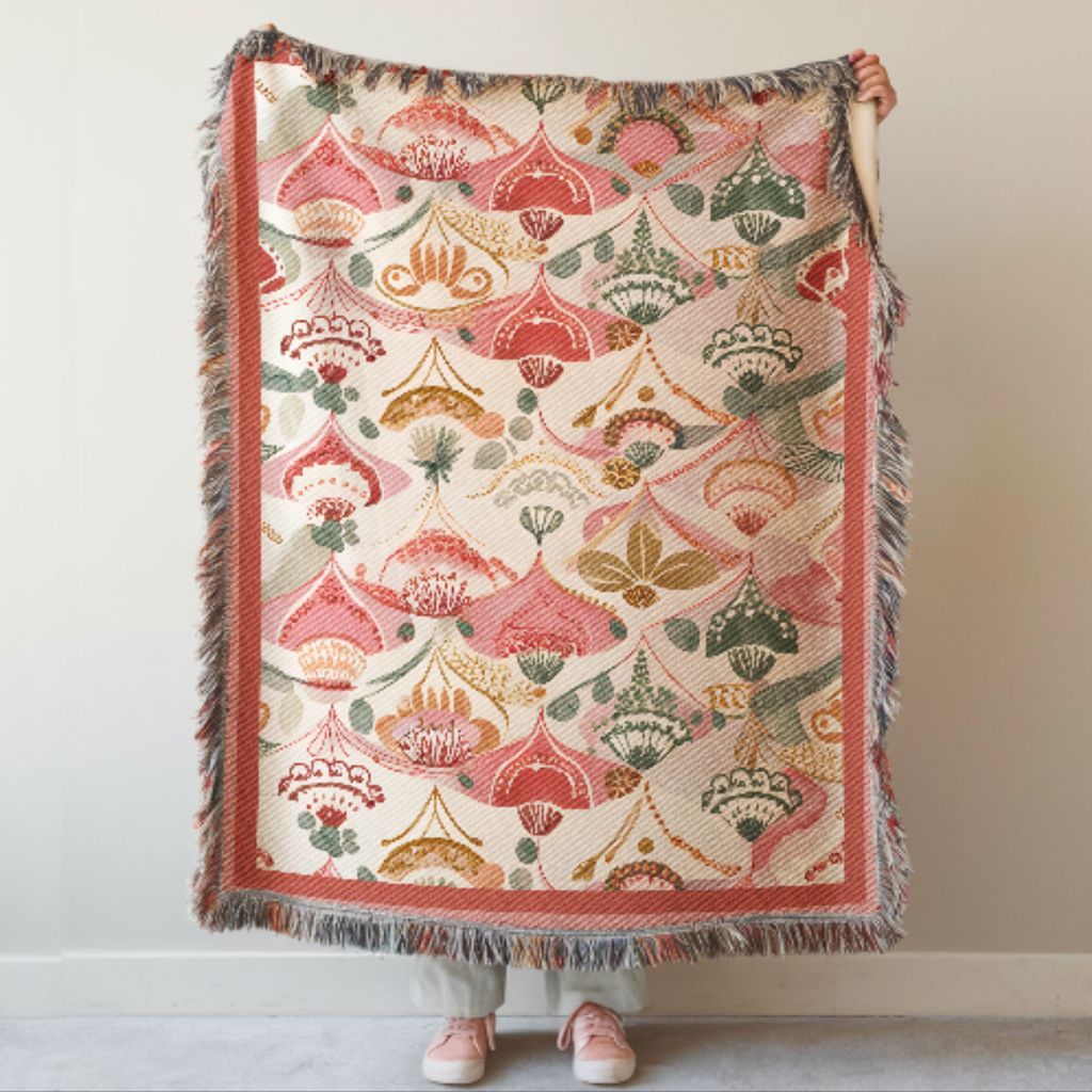 Pink Boho Woven Blanket with intricate patterns held by a person against a plain background