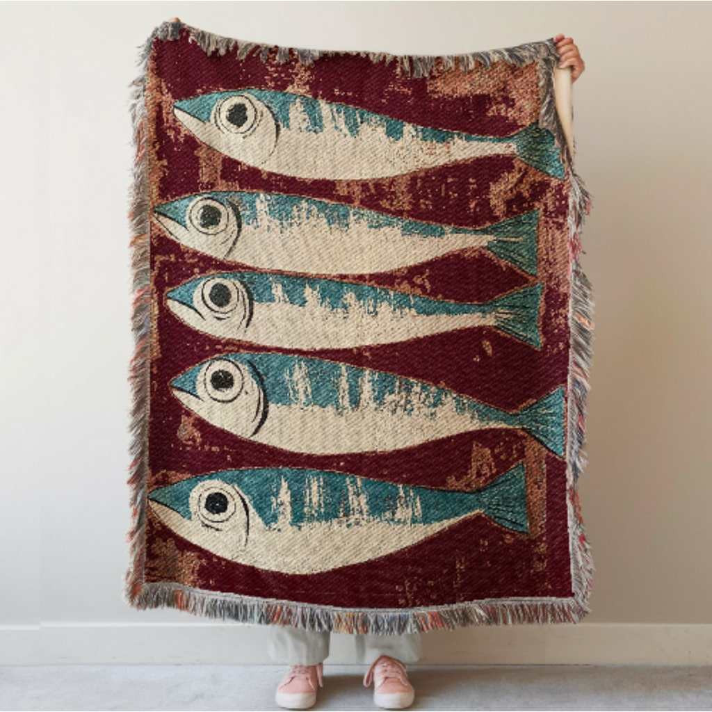 Sardines Woven Blanket with fish pattern held by a person against a plain background