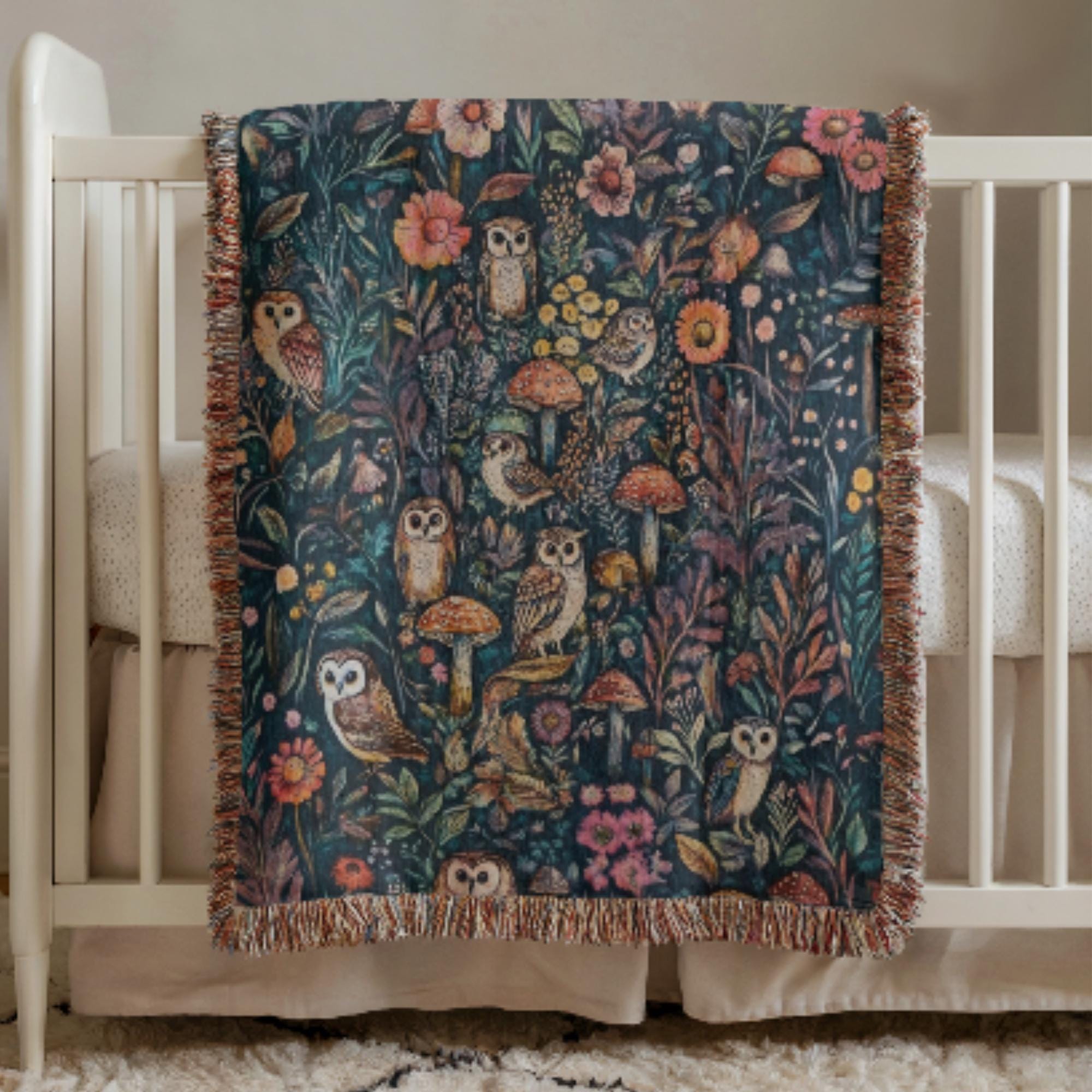 Woodland Owl Woven Baby Blanket with owl and floral pattern draped over a crib