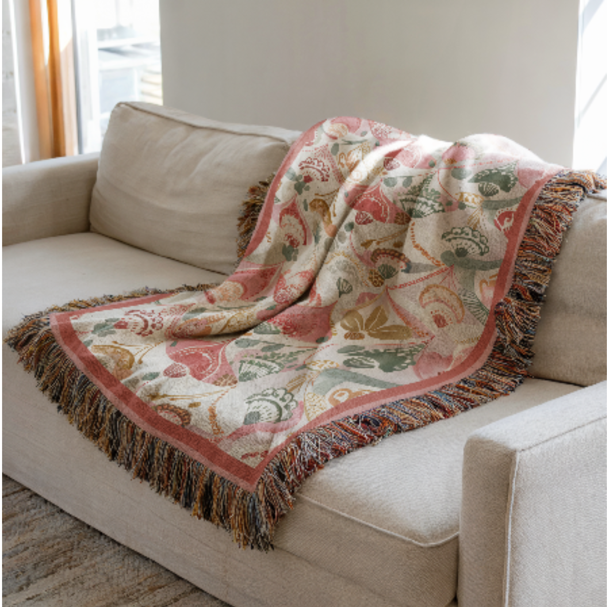 Decorative boho blanket with floral pattern draped over a beige sofa.