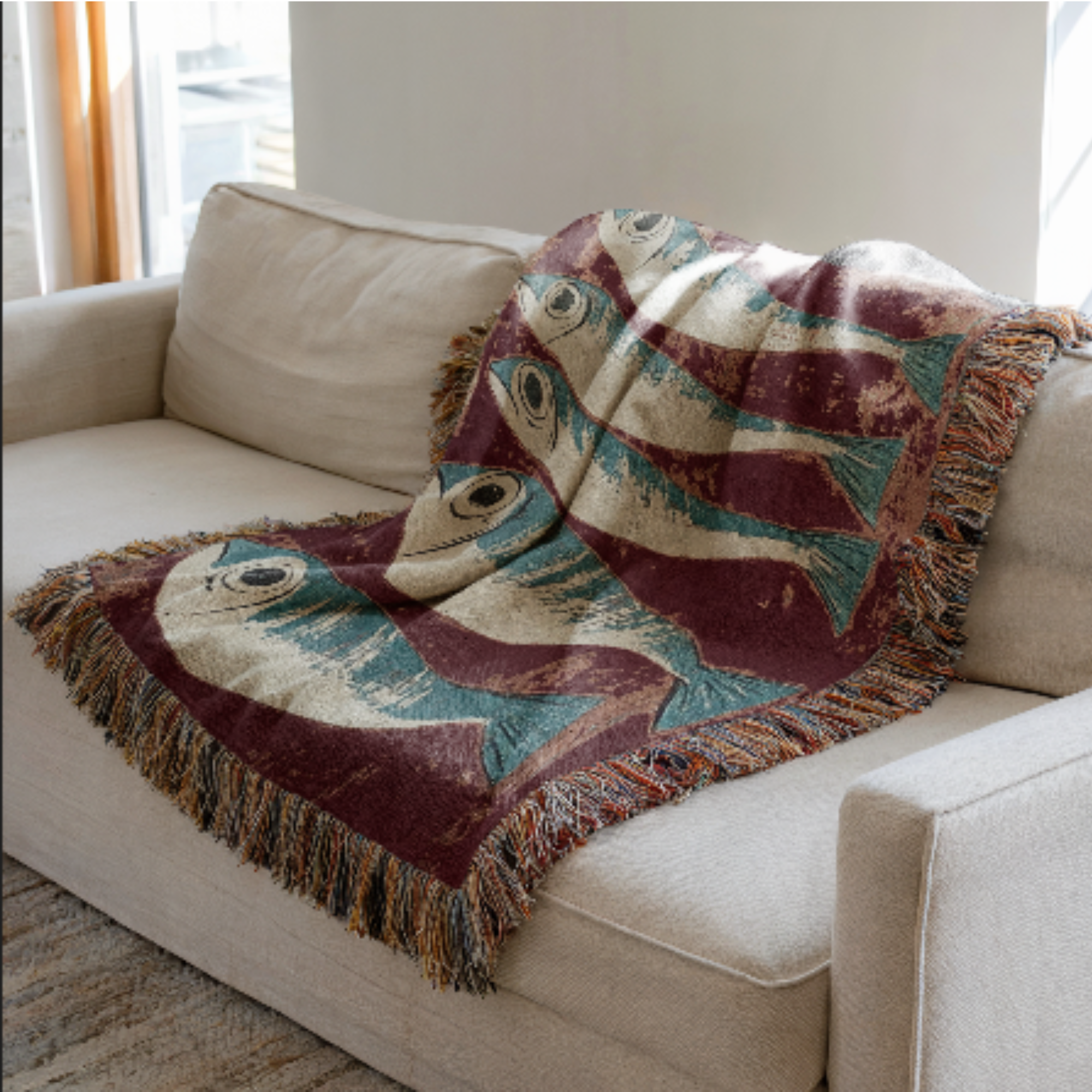 Decorative sardines woven blanket with fish pattern draped over a beige sofa.