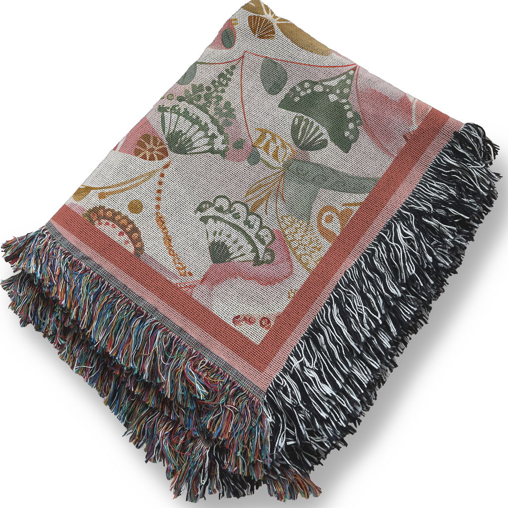 Decorative pink boho throw blanket with fringe on a white background