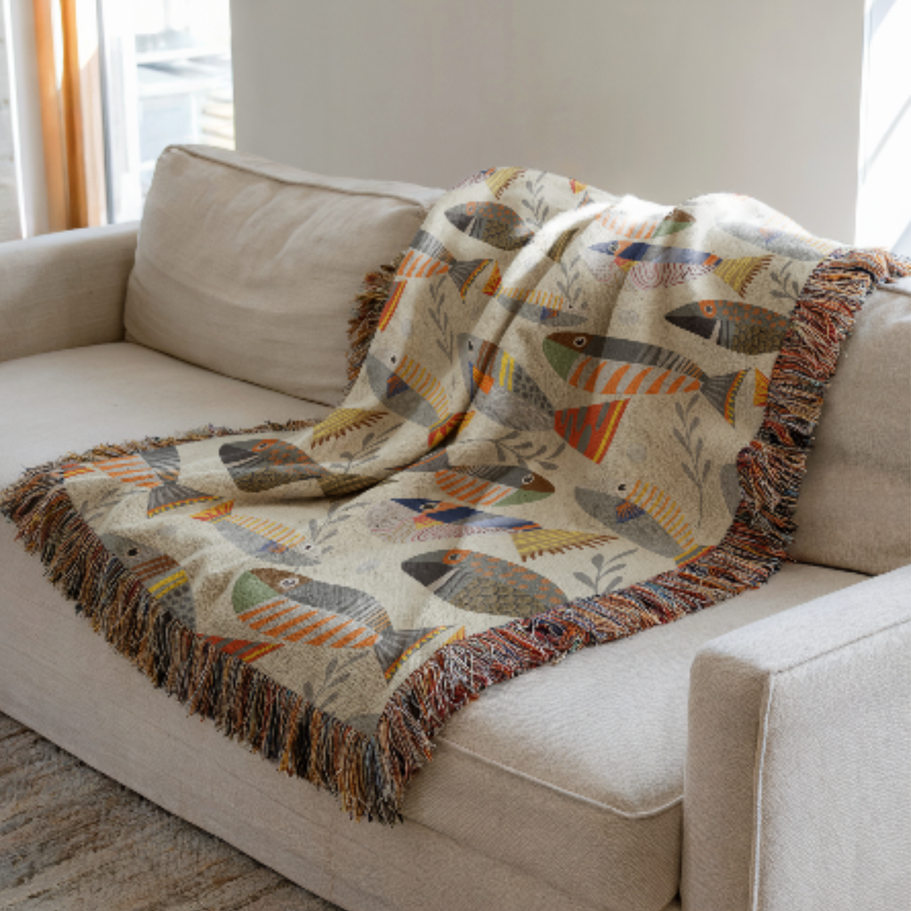 Fish-patterned woven blanket draped over a beige sofa in a living room.